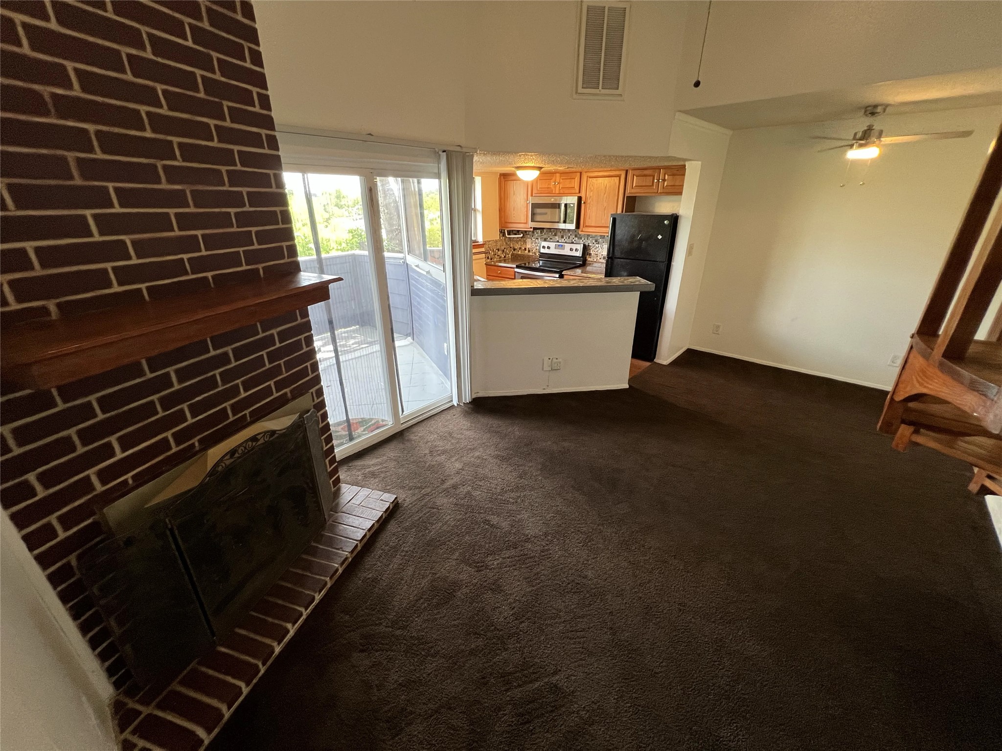 2500 Burleson Road, Unit 622 Austin, TX 78741 - Photo 3 of 17 A cozy living space boasts a brick fireplace and seamlessly transitions to the kitchen and outdoor balcony.
