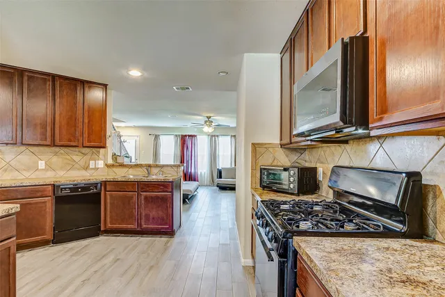 a kitchen with stainless steel appliances granite countertop a stove a sink and a microwave