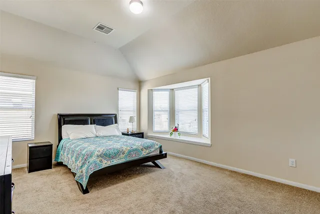 a bedroom with a bed lamp and a large window