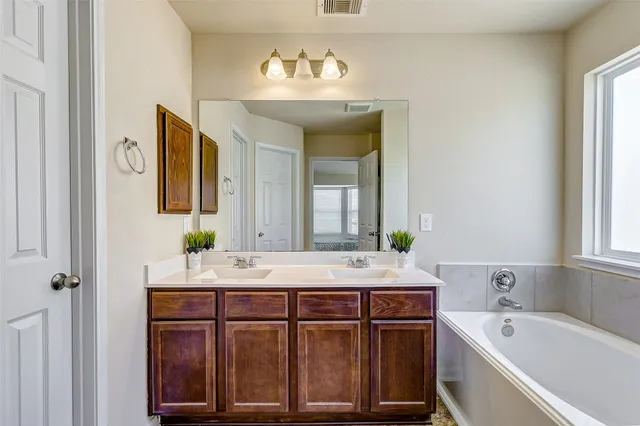 a bathroom with a tub sink and mirror