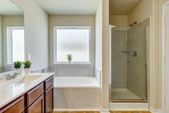 a bathroom with a granite countertop sink a mirror a bathtub and shower