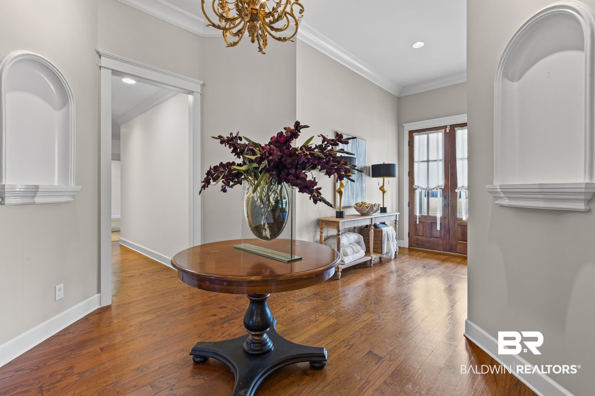 11261 Halcyon Loop Daphne, AL 36526 - Photo 5 of 41 Entryway featuring wood-finish flooring, a decorative chandelier, dual arched wall niches, and a paneled double-door entry with glass inserts