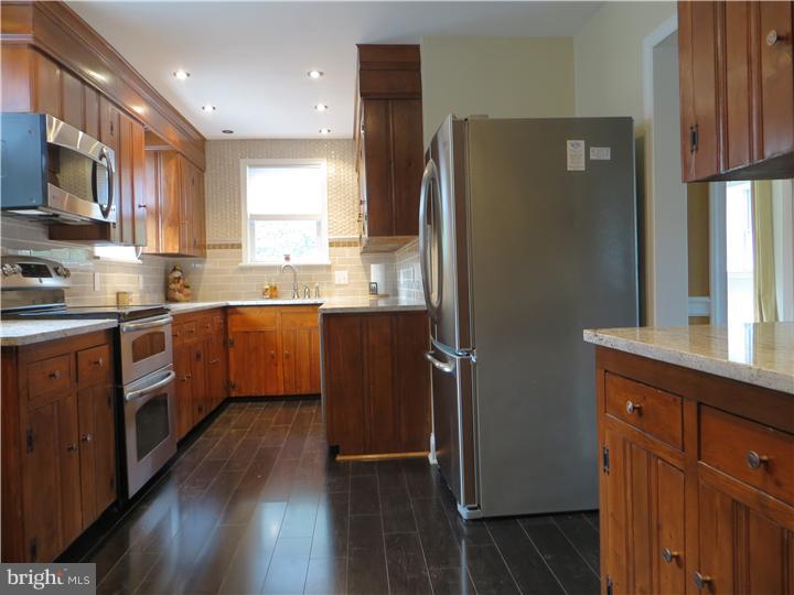 108 Grubb Road Malvern, PA 19355 - Photo 5 of 23 a kitchen with stainless steel appliances granite countertop a refrigerator a sink dishwasher a stove with wooden cabinets and floor