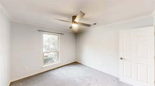 an empty room with a fan & a window