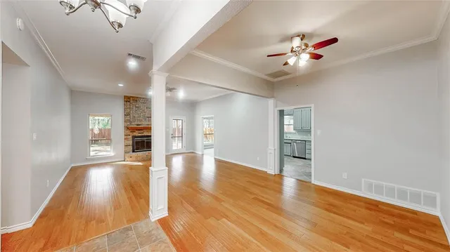 a view of an empty room with wooden floor and a ceiling fan
