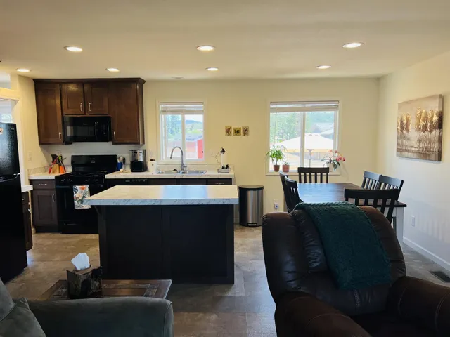 a living room with furniture a flat screen tv and kitchen view
