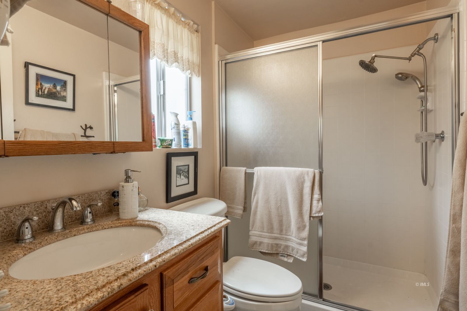 234 Brook Lane Bishop, CA 93514 - Photo 17 of 33 a bathroom with a granite countertop sink toilet a mirror a shower and a window