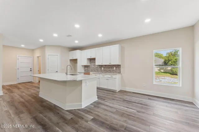 a large kitchen with kitchen island a sink a center island stainless steel appliances and a window