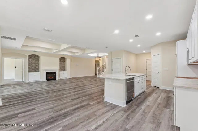a large white kitchen with wooden floors and white cabinets