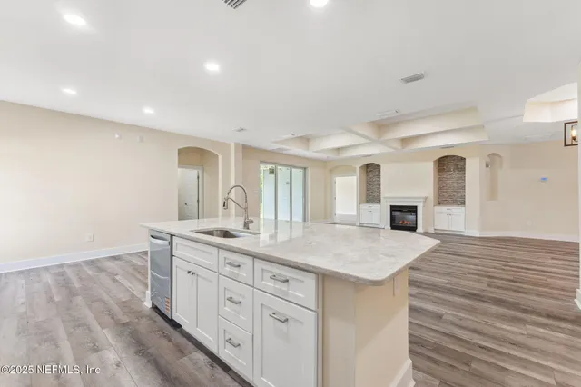 a kitchen with a sink dishwasher a dining table and chairs with wooden floor