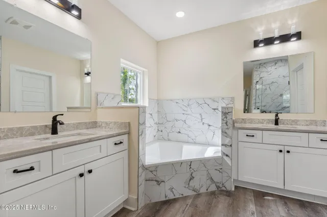 a spacious bathroom with a granite countertop sink mirror and bathtub