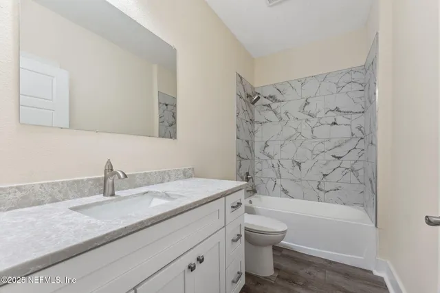 a bathroom with a granite countertop sink a toilet and shower