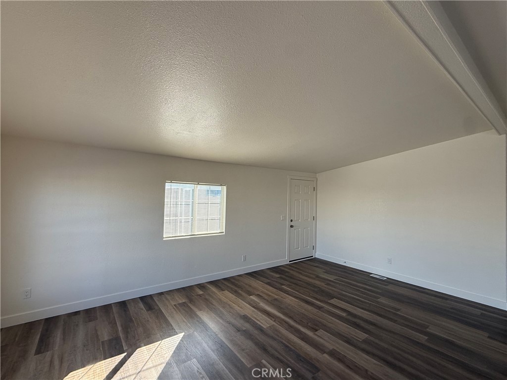 7850 Slater Avenue, Unit 99 Huntington Beach, CA 92647 - Photo 5 of 16 an empty room with wooden floor and windows