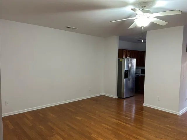 a view of a room with wooden floor and a ceiling fan