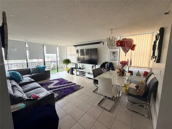 a living room with furniture a flat screen tv and a window