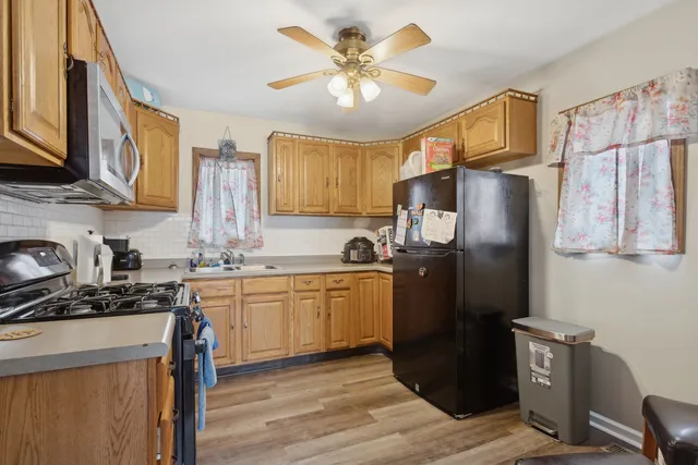 a kitchen with stainless steel appliances granite countertop a refrigerator a stove a sink and dishwasher with wooden floor