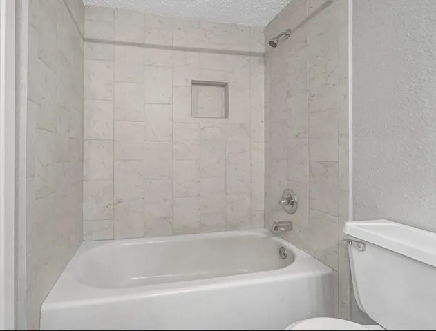 a white bath tub sitting next to a white toilet and a shower