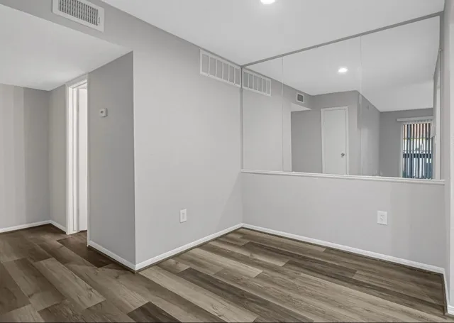 a view of empty room with wooden floor and fan
