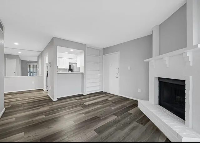 a view of a livingroom with wooden floor and a fireplace