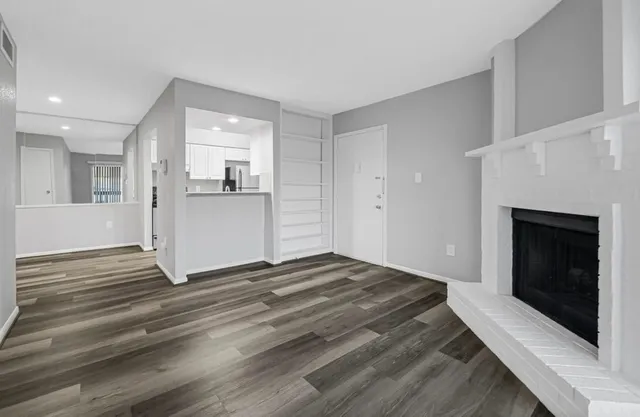 a view of empty room with wooden floor and fireplace