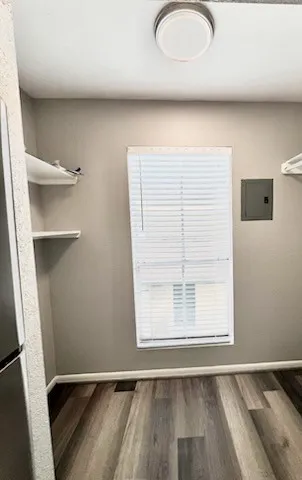 a view of an empty room with a window and wooden floor