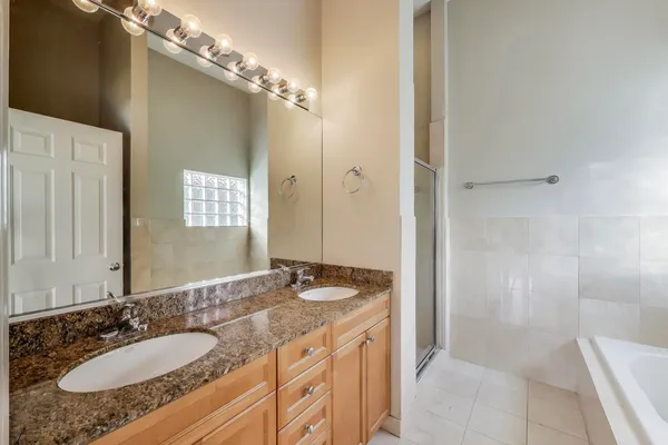 a bathroom with a granite countertop double vanity sink and mirror