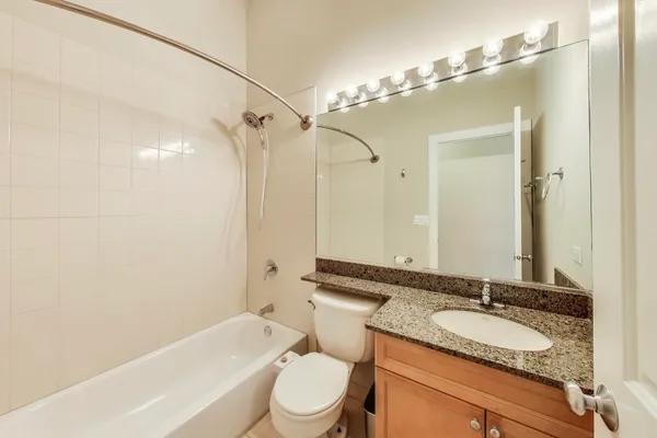 a bathroom with a granite countertop sink toilet mirror and shower