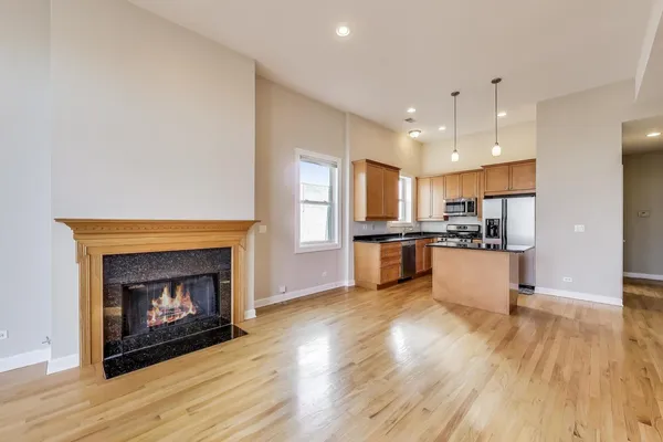 a view of kitchen with kitchen island wooden floor and fireplace