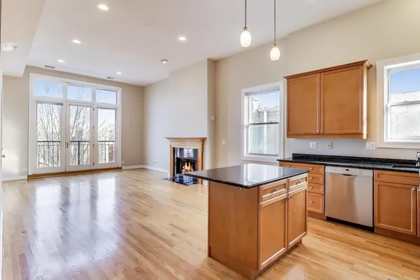 a kitchen with granite countertop a stove a sink a center island and wooden floor