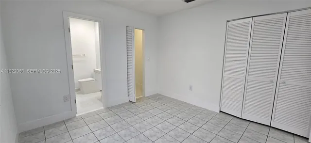 a view of an empty room with window and chandelier fan