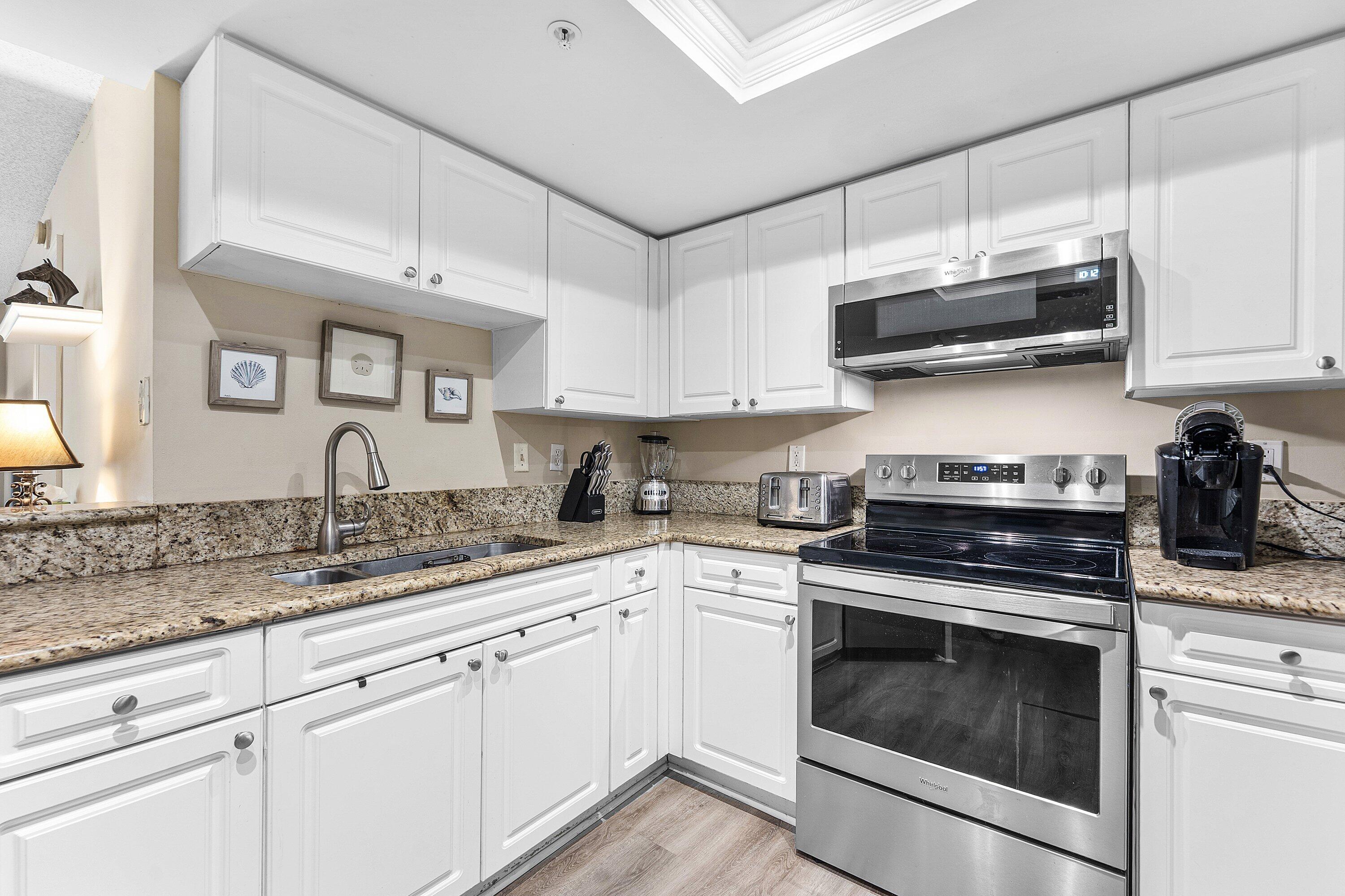 1000 Crestwood Court South, Unit 1015 Royal Palm Beach, FL 33411 - Photo 3 of 21 a kitchen with stainless steel appliances granite countertop white cabinets a sink and dishwasher a stove top oven with white countertops
