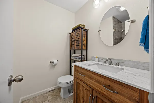 a bathroom with a granite countertop toilet sink mirror and vanity