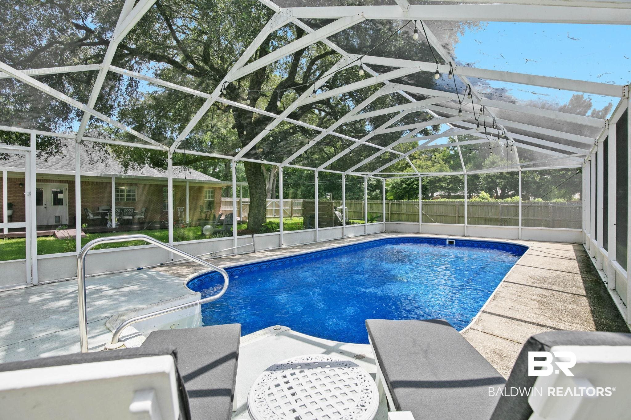 520 Juniper Place Drive Foley, AL 36535 - Photo 30 of 35 Screened swimming pool enclosure featuring a rectangular pool with integrated steps, concrete decking, and string lighting