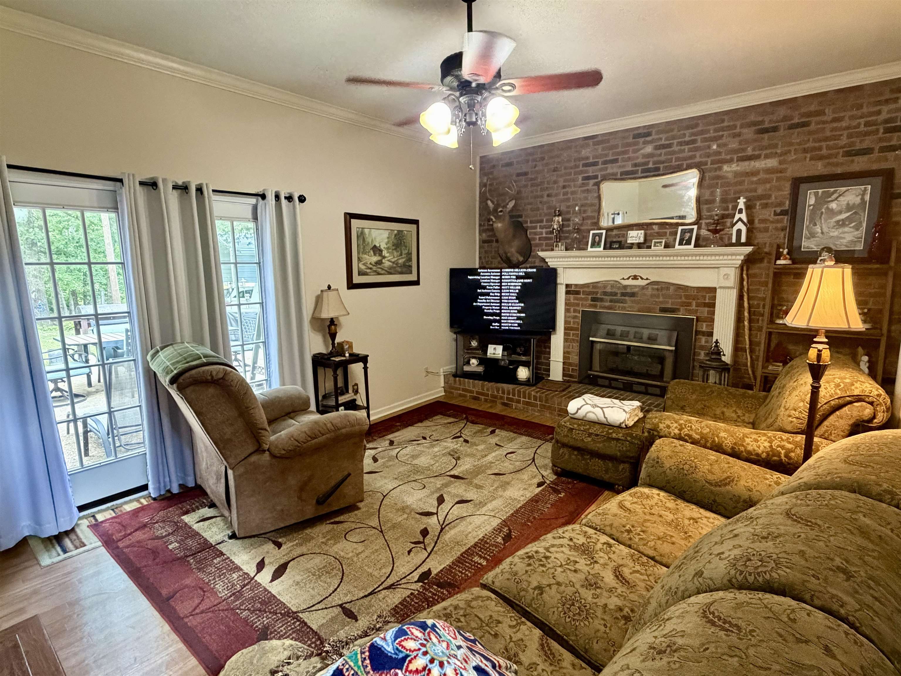 142 Treece Street Selmer, TN 38375 - Photo 2 of 36 Living area featuring a brick accent wall, white crown molding, and wood-finish flooring