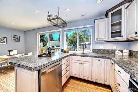 a kitchen with granite countertop stainless steel appliances a stove center island a cabinets and a large window
