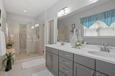 a bathroom with a tub a sink double vanity and a mirror