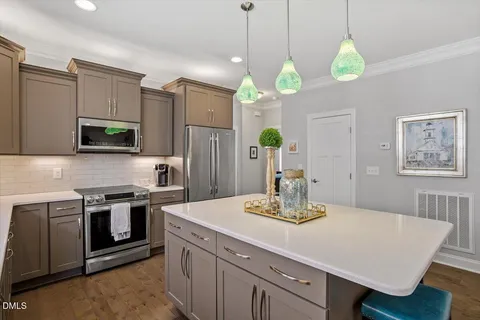 a kitchen with stainless steel appliances granite countertop a sink a stove a refrigerator cabinets and wooden floor