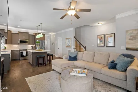 a living room with furniture kitchen view and a wooden floor