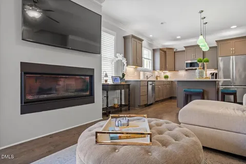 a living room with stainless steel appliances kitchen island granite countertop furniture a fireplace and a flat screen tv