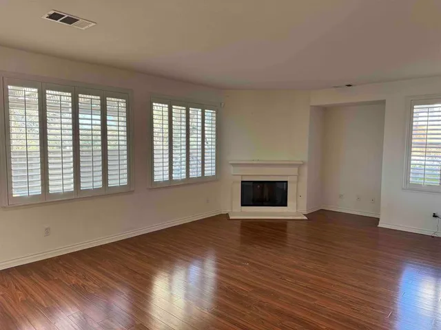 an empty room with wooden floor and chandelier