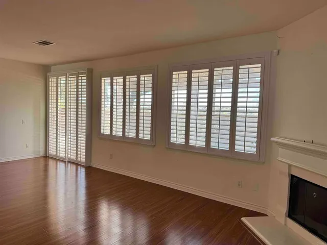 a view of an empty room with a window and wooden floor
