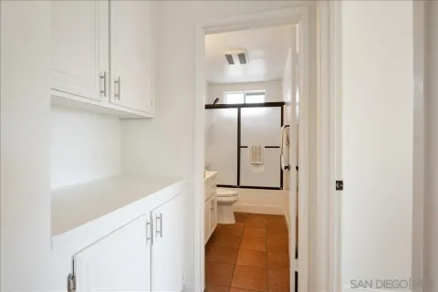 a hallway with white cabinets and wooden floor