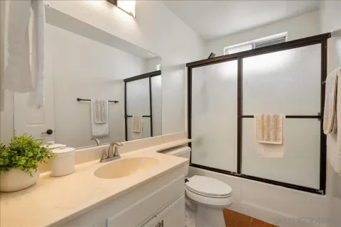 a bathroom with a granite countertop sink toilet and mirror