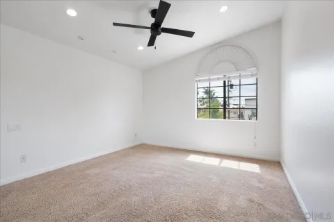 an empty room with windows and ceiling fan