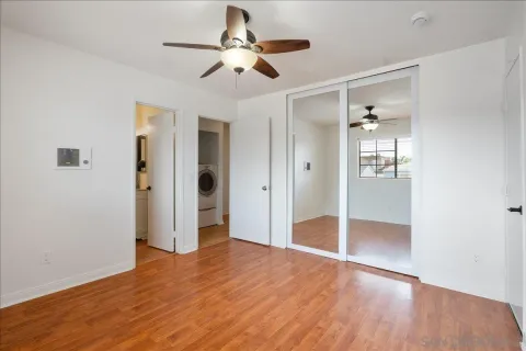a view of empty room with wooden floor and ceiling fan