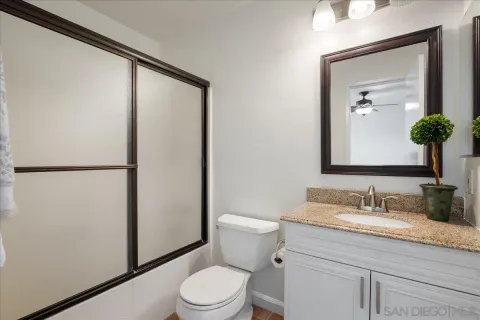 a bathroom with a granite countertop sink a toilet and mirror