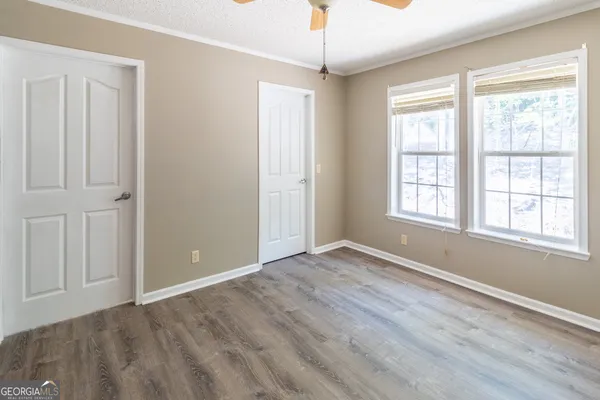 a view of an empty room with a window and wooden floor