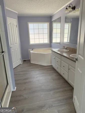 a spacious bathroom with a granite countertop double vanity sink a mirror and a bathtub