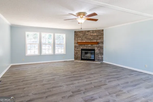 an empty room with wooden floor fan and windows