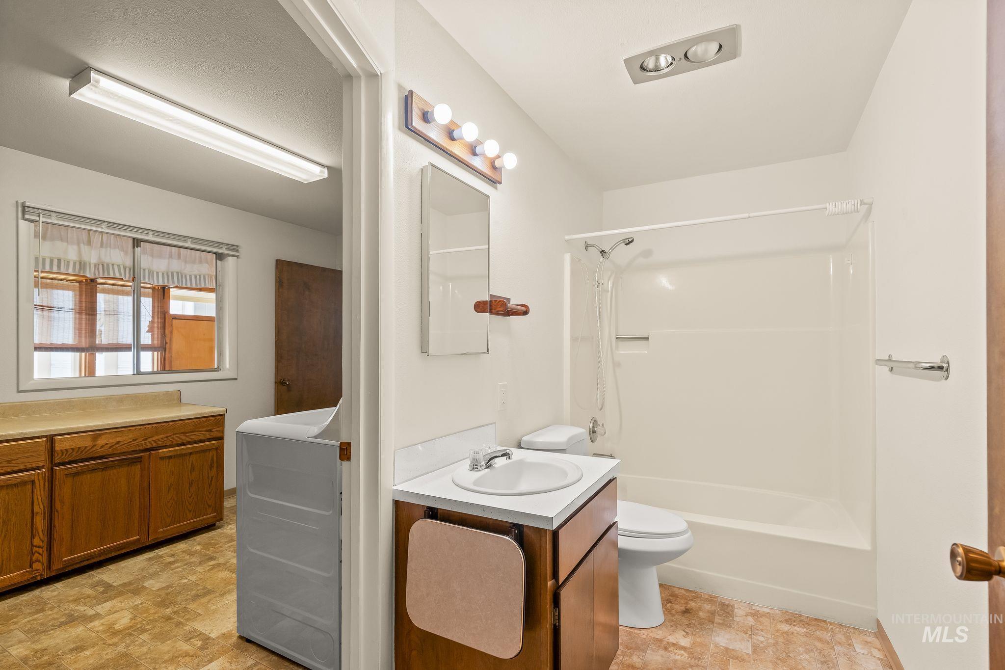 1721 3rd Street Lewiston, ID 83501 - Photo 37 of 45 Bathroom featuring a white vanity with integrated sink, a commode, and a shower-tub combination with white surround